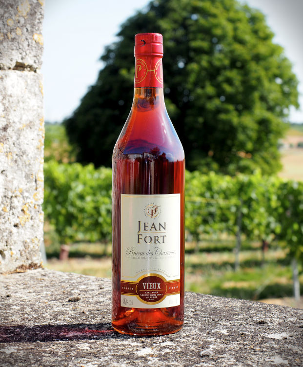 Bouteilles de Pineau des Charentes blanc et rosé du producteur Jean Fort, avec des verres de dégustation.